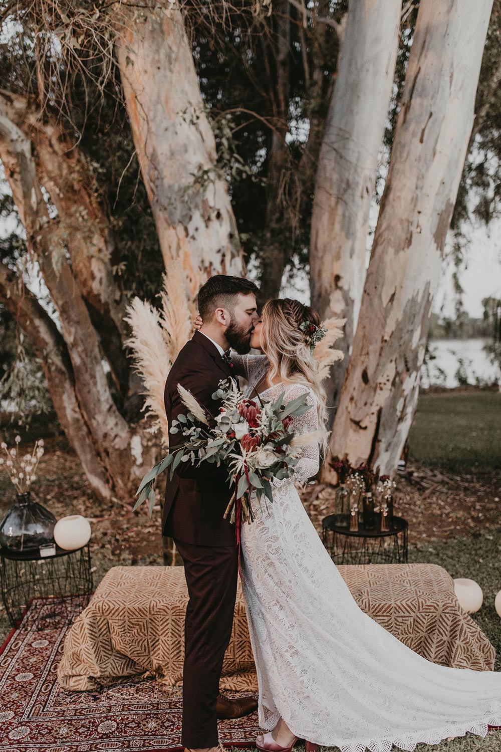 lace wedding dress and burgundy groom suit with pampas grass wedding backdrop