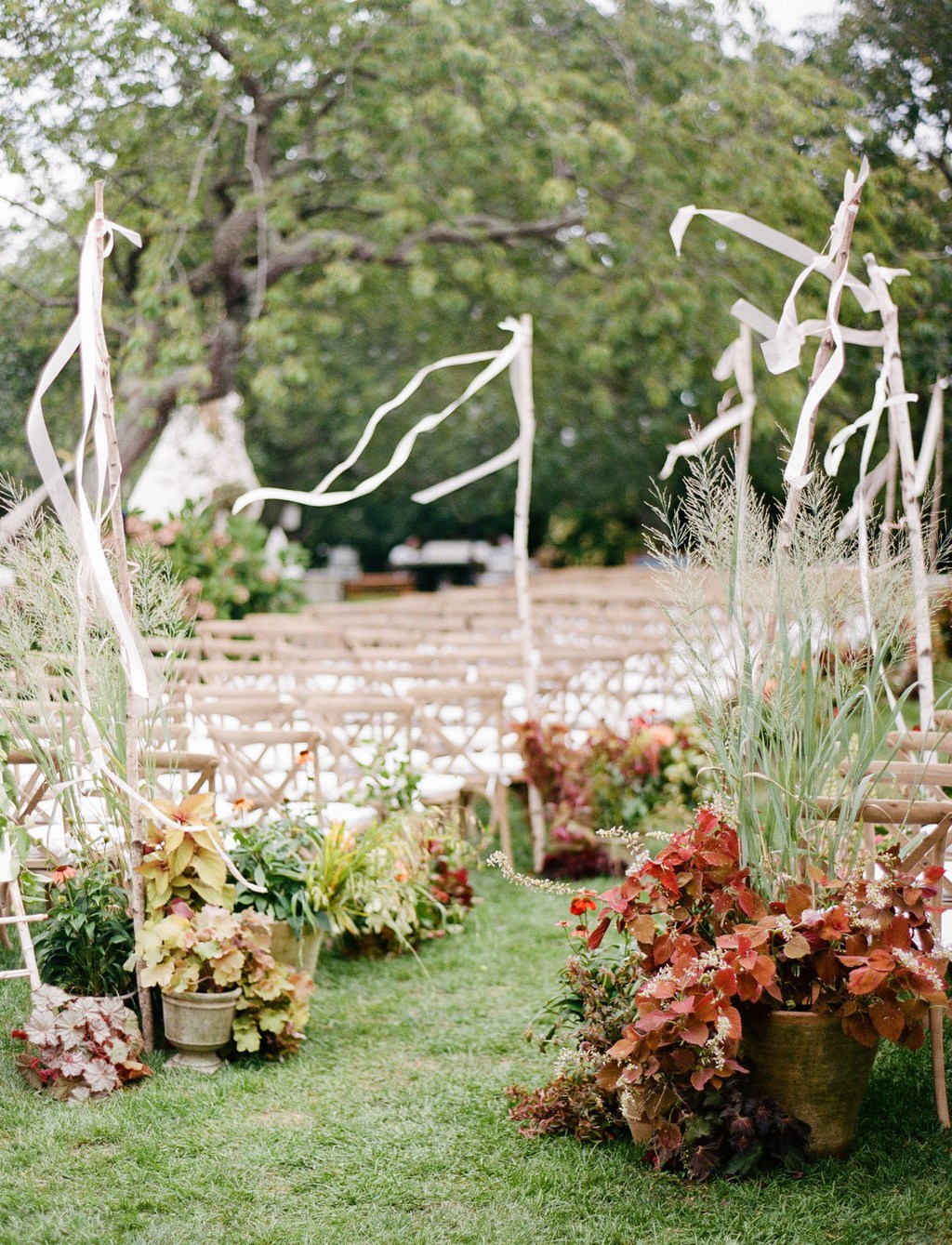 fall wedding aisle with planted arrangements and ribbon stakes