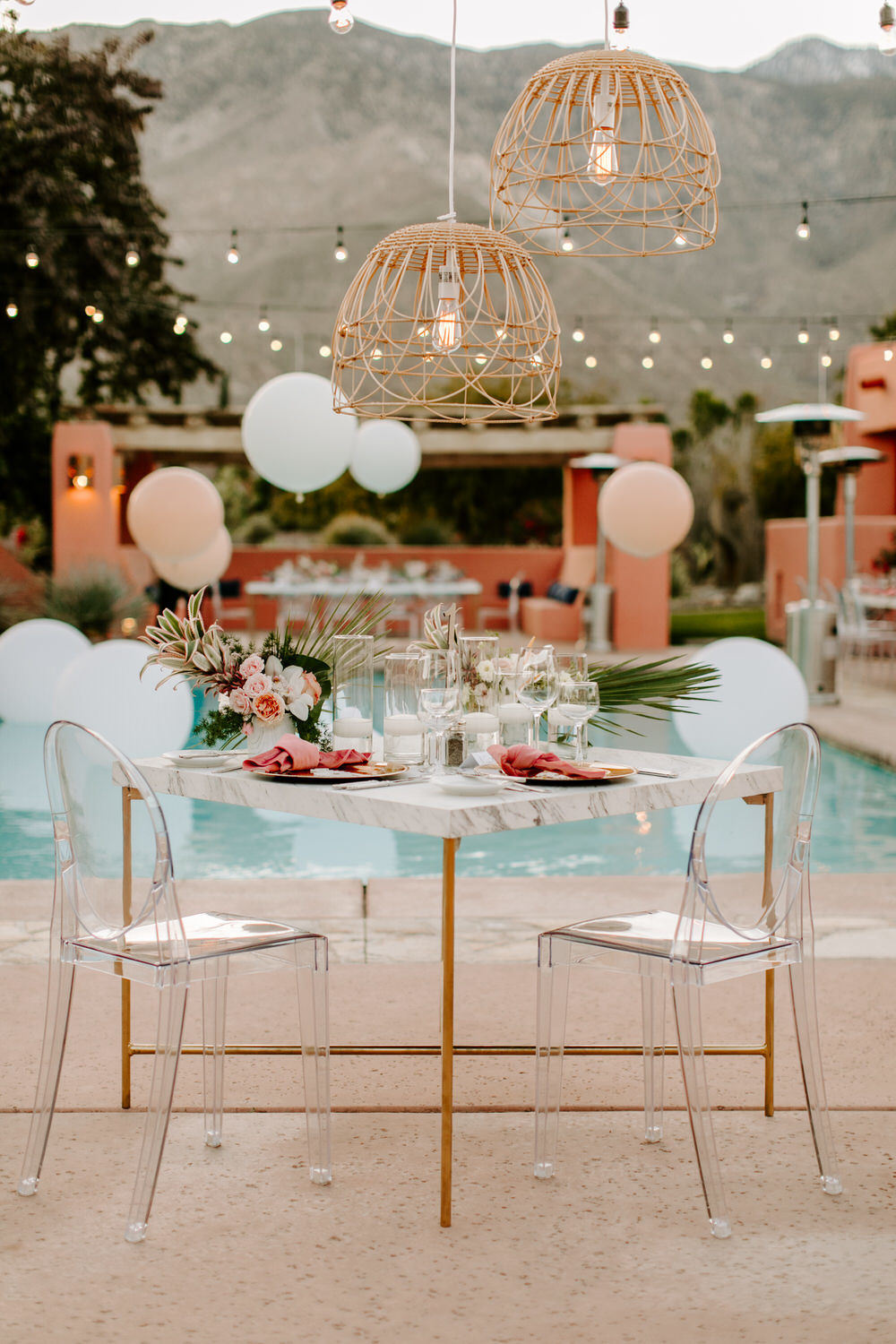 sweetheart table with ghost chairs, marble table and pink tropical accents